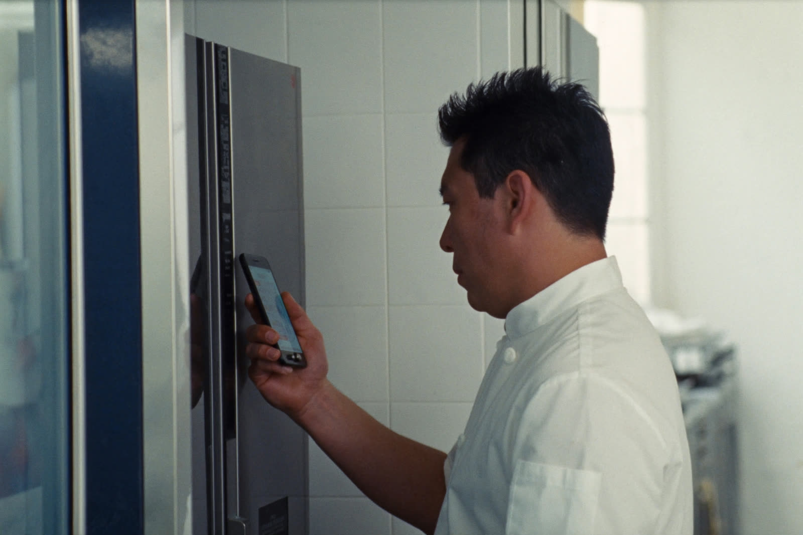 Cuisinier qui relève la température d'un frigo avec son téléphone